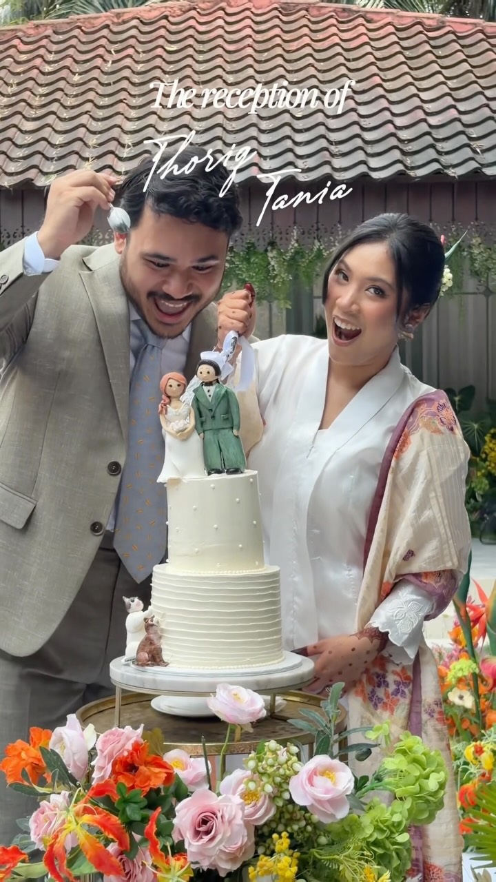 A smiling couple beside a tiered wedding cake topped with two figurines